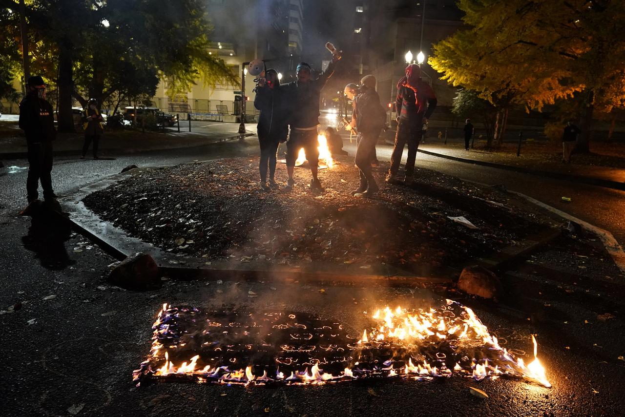 Un drapeau américain brûlé à Portland. [Keystone - AP/Marcio Jose Sanchez]