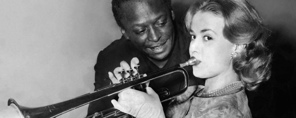 Le trompettiste de jazz américain Miles Davis donne une leçon de trompette à l'actrice française Jeanne Moreau (Paris, 1957). [AFP]