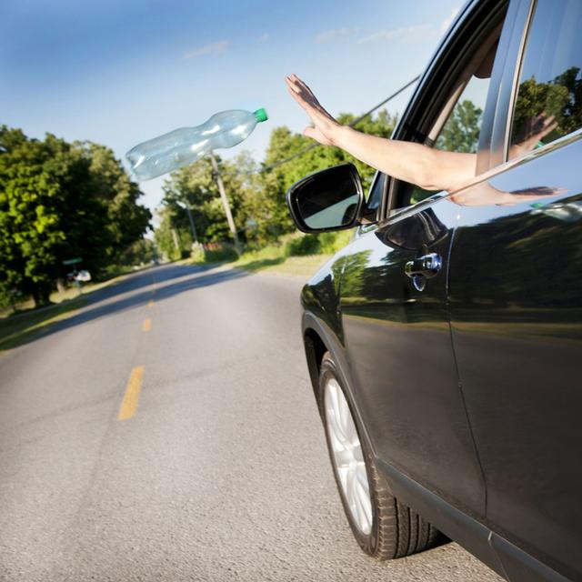 Une personne jette un déchet par la fenêtre de sa voiture. [Depositphotos - Justek16]