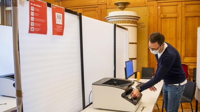 Un scrutateur scanne les bulletins de vote lors des élections communales dans le canton de Neuchâtel. [Keystone - Jean-Christophe Bott]