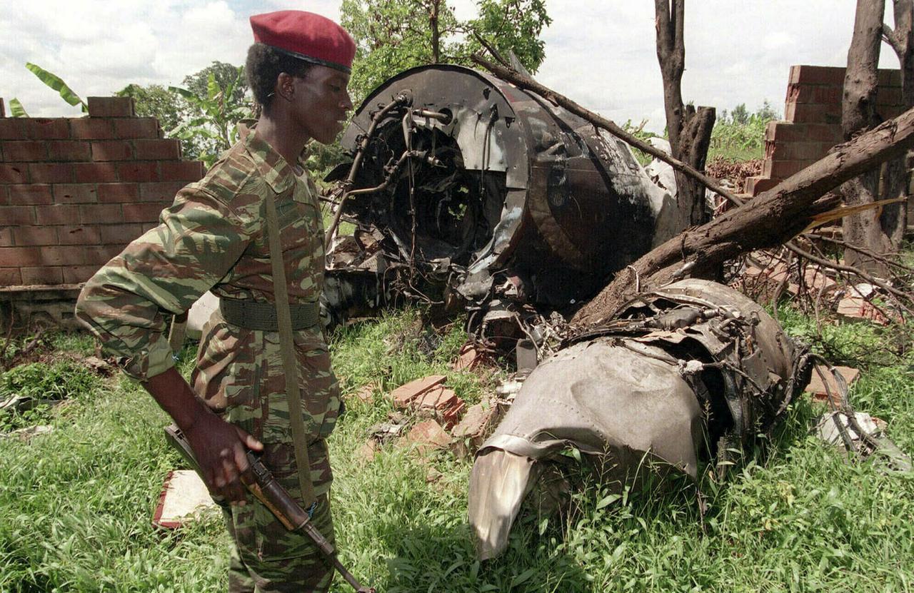 Sur cette photo prise le 23 mai 1994, un rebelle du Front patriotique rwandais (FPR) marche près des restes de l'avion du président rwandais Juvenal Habyarimana, abattu le 6 avril 1994 à Kigali (Rwanda). Cet attentat fut l'élément déclencheur du génocide de 800'000 Tutsi et Hutu modérés, massacrés par la majorité Hutu en 100 jours. Il s'agit du pire génocide de l'histoire récente. [AP/Keystone - Jean-Marc Bouju]