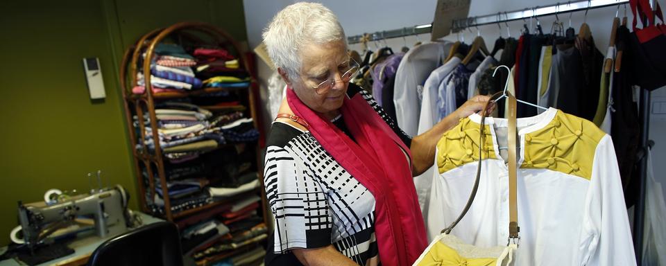 Une femme regarde des vêtements dans une "ressourcerie", un magasin associatif et solidaire qui collecte et répare les articles perdus pour les revendre à bas prix. [AFP - Thomas Samson]