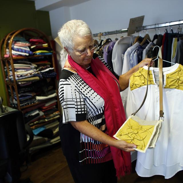 Une femme regarde des vêtements dans une "ressourcerie", un magasin associatif et solidaire qui collecte et répare les articles perdus pour les revendre à bas prix. [AFP - Thomas Samson]