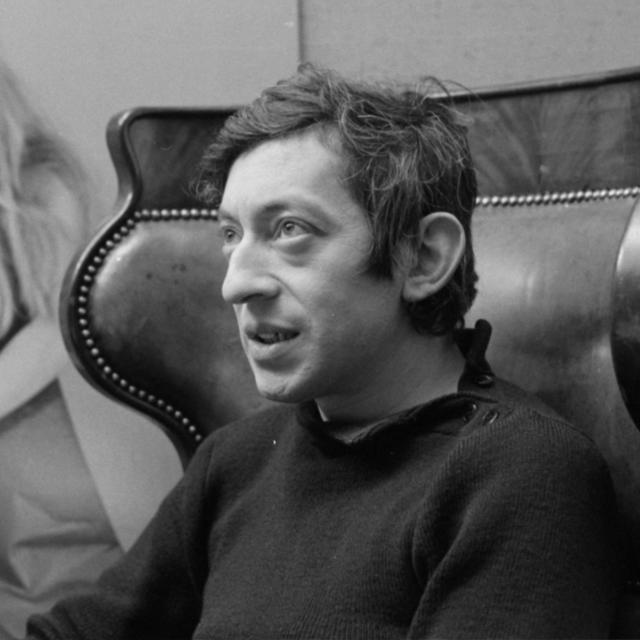 Portrait de Serge Gainsbourg, une photographie de Brigitte Bardot en arrière plan, dans l'émission "Entrez dans la confidence" réalisée par Jacqueline Joubert. [Ina via AFP - Daniel Lefevre]