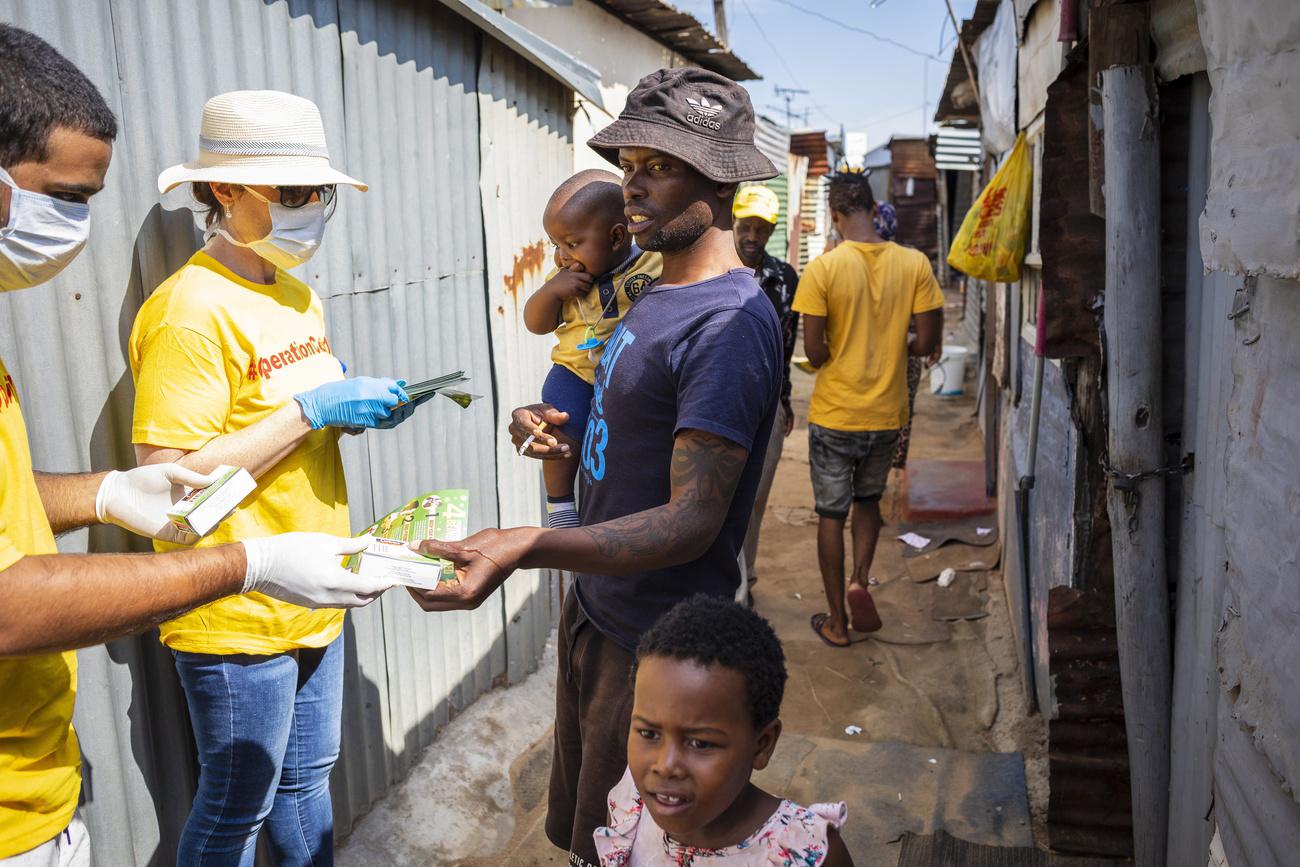 Des bénévoles de l"Opération Covid-19" distribuent des papillons d'information ainsi que du savon aux résidents du Township de Diepsloot à Johannesburg. Afrique du Sud, le 21 mars 2020. [Keystone/epa - Kim Ludbrook]