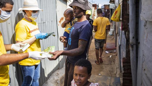 Des bénévoles de l"Opération Covid-19" distribuent des papillons d'information ainsi que du savon aux résidents du Township de Diepsloot à Johannesburg. Afrique du Sud, le 21 mars 2020. [Keystone/epa - Kim Ludbrook]