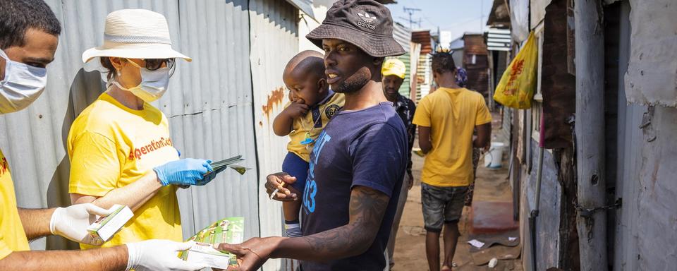 Des bénévoles de l"Opération Covid-19" distribuent des papillons d'information ainsi que du savon aux résidents du Township de Diepsloot à Johannesburg. Afrique du Sud, le 21 mars 2020. [Keystone/epa - Kim Ludbrook]