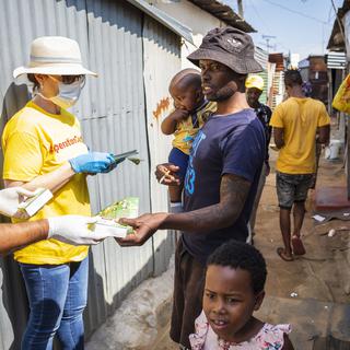 Des bénévoles de l"Opération Covid-19" distribuent des papillons d'information ainsi que du savon aux résidents du Township de Diepsloot à Johannesburg. Afrique du Sud, le 21 mars 2020. [Keystone/epa - Kim Ludbrook]