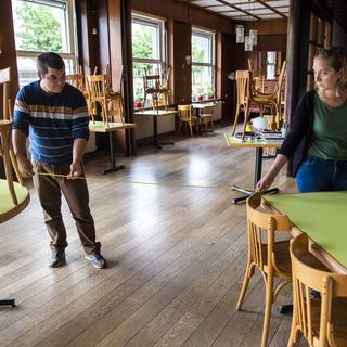 Les gérants du restaurant "Le Café des Avenues" à Lausanne mettent en place le dispositif de distance de deux mètres entre les tables en vue du 11 mai. [Keystone - Jean-Christophe Bott]