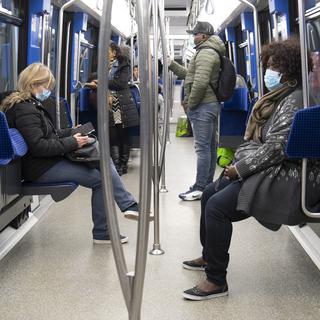 Des personnes munies de masques d'hygiène dans le métro M2 à Lausanne le 23 mars 2020. [Keystone - Laurent Gilliéron]