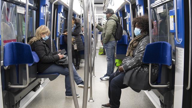 Des personnes munies de masques d'hygiène dans le métro M2 à Lausanne le 23 mars 2020. [Keystone - Laurent Gilliéron]