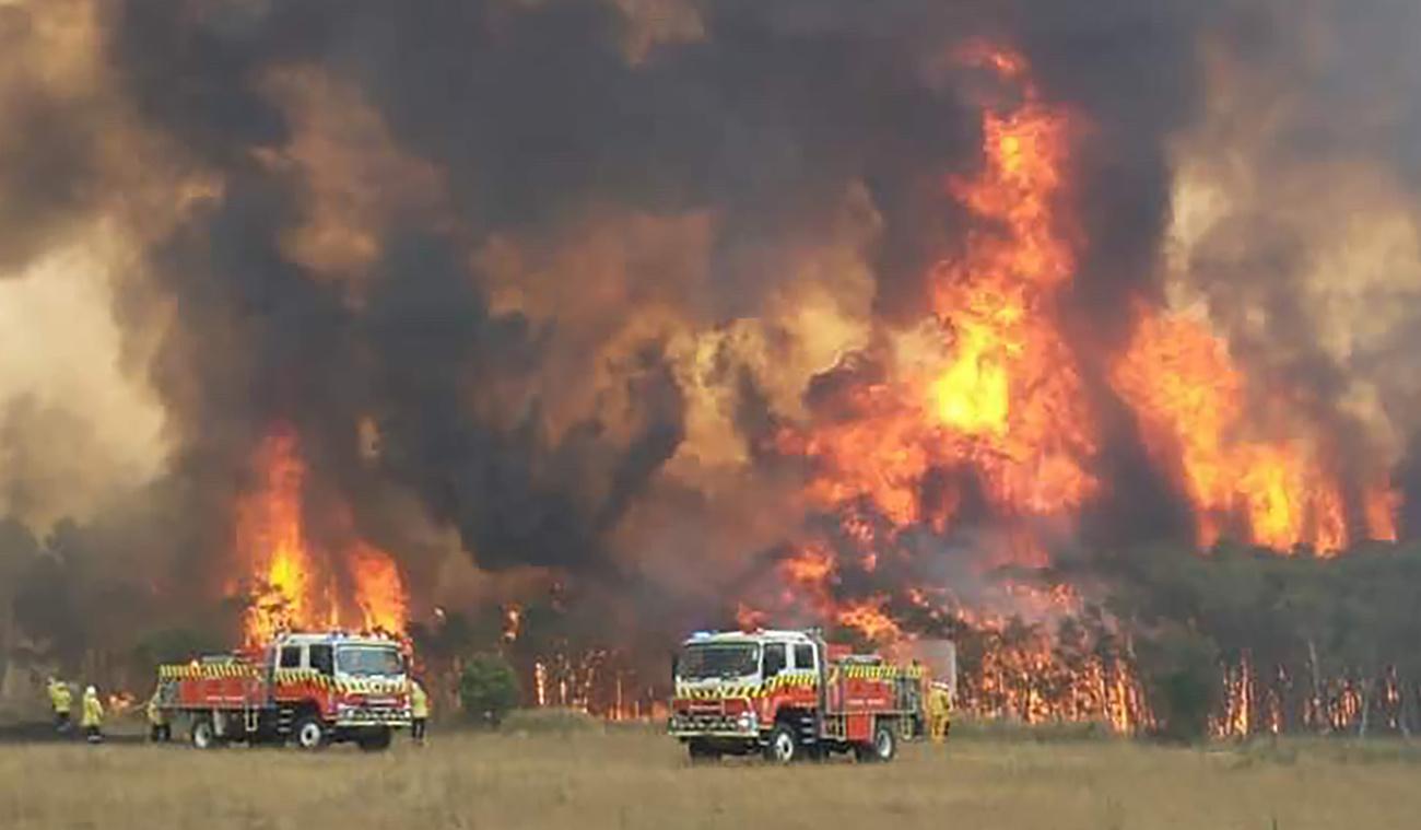 Des pompiers impuissants tentent de protéger des habitations à Charmhaven, en Nouvelle-Galles du Sud. [Keystone - Twitter@NSWRFS via AP]