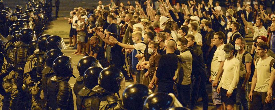 Des manifestants face à la police à Minsk, en Biélorussie, après les élections présidentielles. [AP/Keystone]