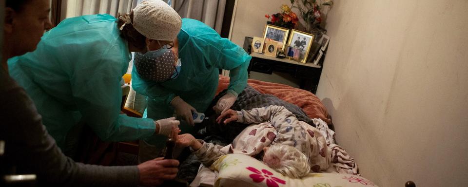 Des infirmiers s'occupent d'une patiente durant la pandémie de coronavirus à Barcelone, en Espagne. [EPA/Keystone - Enric Fontcuberta]