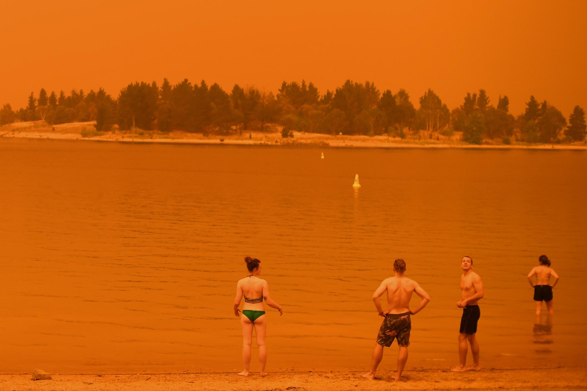 Des résidents sur une plage aux couleurs apocalyptiques, au bord du Lac Jindabyne, en Nouvelle-Galles du Sud. [afp - Saeed Khan]