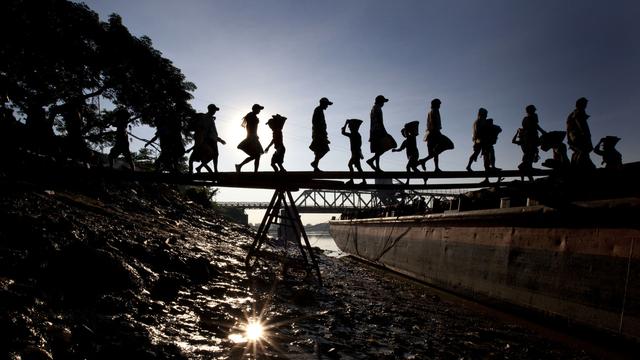 Des enfants déchargent du gravier d'un bateau au Myanmar. [Keystone - AP/Gemunu Amarasinghe]