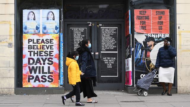 Des piétons devant une boutique fermée, à Londres, en pleine pandémie. [KEYSTONE - ANDY RAIN]