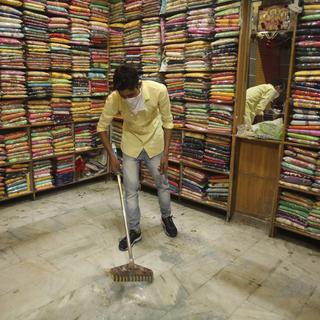 Dimanche 10 mai: un homme nettoie le sol d'un magasin d'habits de Jammu, en Inde. [Keystone - AP/Channi Anand]
