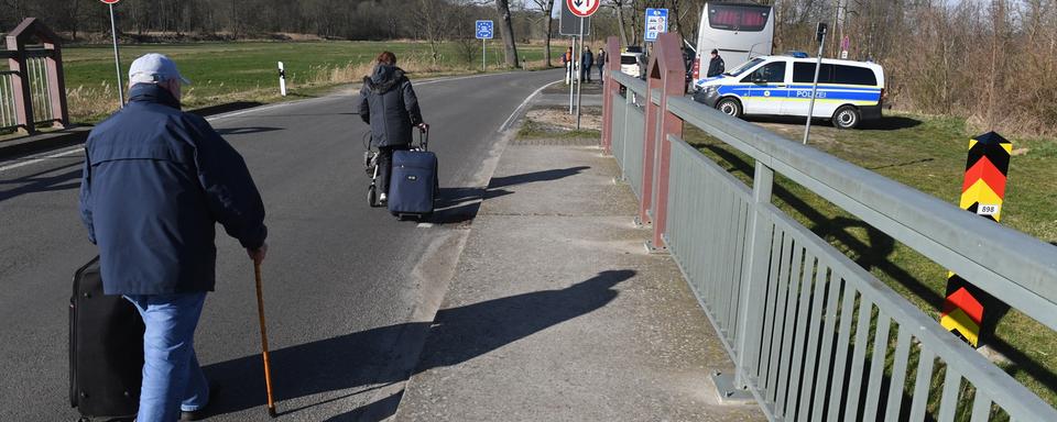 Des touristes quittent la Pologne à pied faute de moyens de transport, 15.03.2020. [DPA/AP/Keystone - Stefan Sauer]