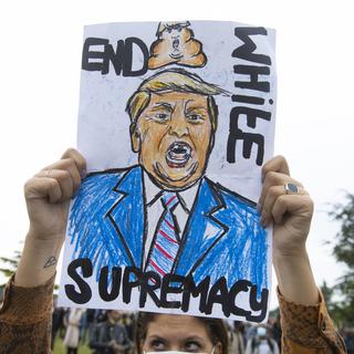 Un panneau faisant de Trump un suprémaciste blanc., [Keystone - AP Photo Peter Dejong]