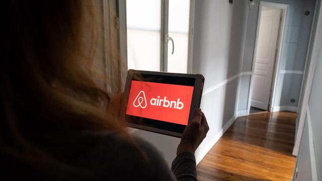 Une femme tient une tablette avec le logo de la plateforme de location Airbnb. [AFP - Hans Lucas]