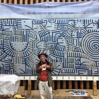 Laurent Possa pose devant la peinture murale faite pour un mur de l'Hôpital de Sion. [RTS - Florence Grivel]