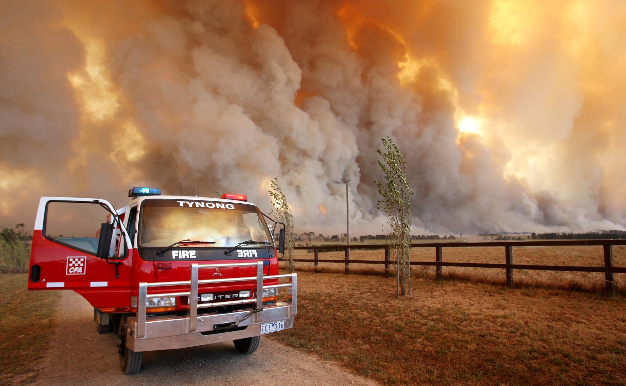 Un camion de pompiers devant un foyer géant qui fait rage près de Labertouche, à l'ouest de Melbourne. [afp - William West]