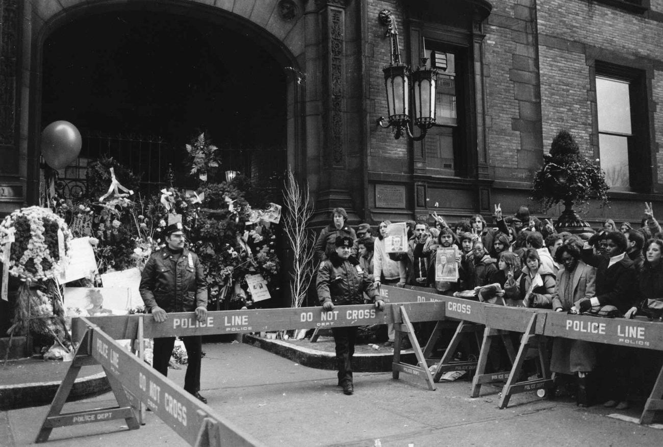 La police tient la foule à distance du Dakota building, la résidence de John Lennon à New York, le 9 décembre 1980, au lendemain de l'annonce de la mort du chanteur. [Keystone - AP Photo/Mario Cabrera]