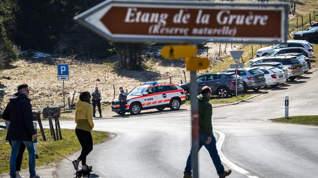 Une patrouille de police contrôle l'accès à l'étang de la Gruère. [Keystone - Jean-Christophe Bott]