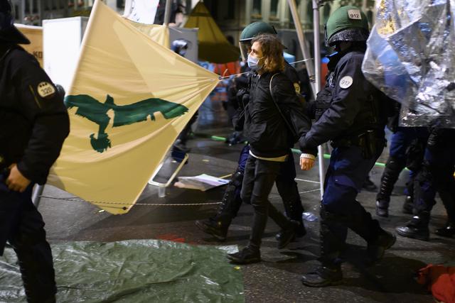 Un activiste pour le climat escorté hors de la Place fédérale par la police bernoise. [Keystone - Anthony Anex]