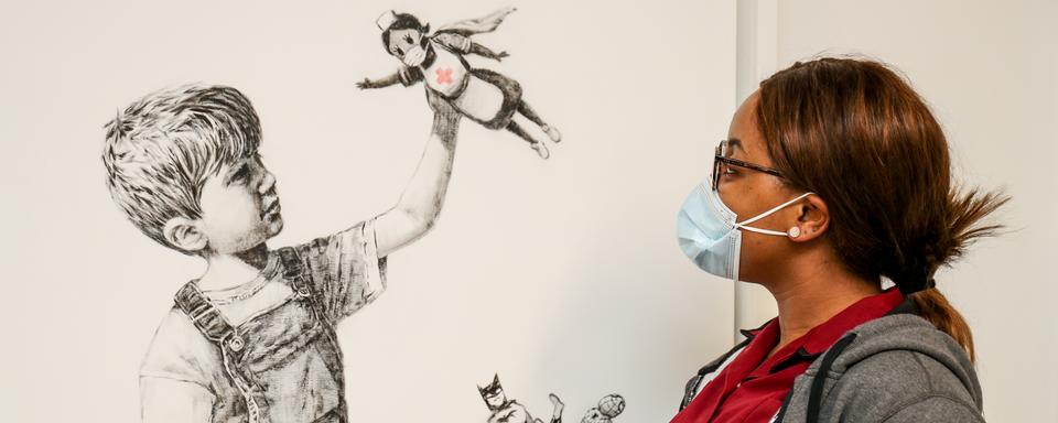 Le street artiste anglais Banksy a rendu hommage au travail des infirmières et infirmiers dans une œuvre qu'il a nommée "Game Changer". Le dessin se trouve sur un mur du University Hospital de Southampton, dans le sud de l'Angleterre. 7 mai 2020. [AFP/ University Hospital Southampton - Stuart Martin]