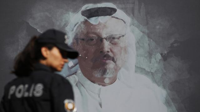 Une policière turque passe devant un portrait du journaliste Jamal Khashoggi, assassiné dans le consulat d'Arabie Saoudite à Istanbul. Octobre 2019. [Keystone/ap photo - Lefteris Pitarakis]