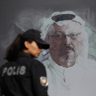 Une policière turque passe devant un portrait du journaliste Jamal Khashoggi, assassiné dans le consulat d'Arabie Saoudite à Istanbul. Octobre 2019. [Keystone/ap photo - Lefteris Pitarakis]
