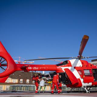 Un hélicoptère de la Rega en train d'évacuer un malade du Covid en direction de l'hôpital de l'Ile à Berne. [Keystone - Jean-Christophe Bott]