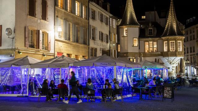 Des personnes assises à la terrasse d'un bar à Neuchâtel, le 25 octobre 2020. [Keystone - Jean-Christophe Bott]