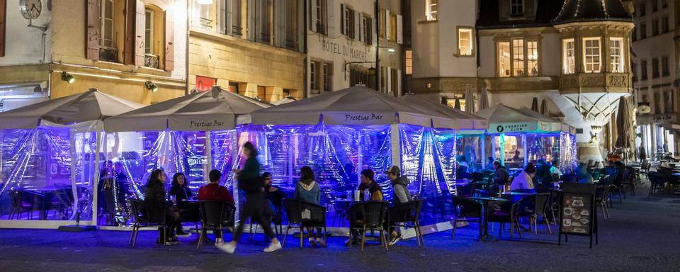 Des personnes assises à la terrasse d'un bar à Neuchâtel, le 25 octobre 2020. [Keystone - Jean-Christophe Bott]