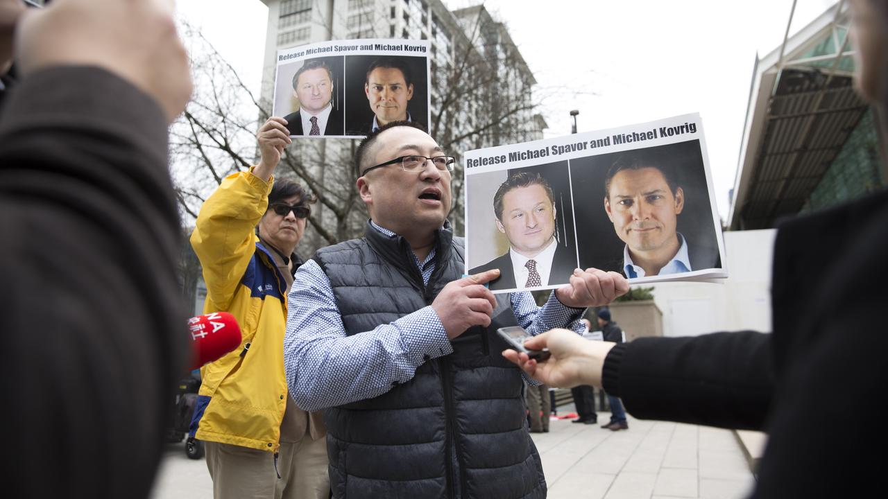 Louis Huang, de l'association Vancouver Freedom and Democracy for China, tient les portraits des Canadiens Michael Spavor et Michael Kovrig, détenus en Chine. Vancouver, le 6 mars 2019. [AFP - Jason Redmond]