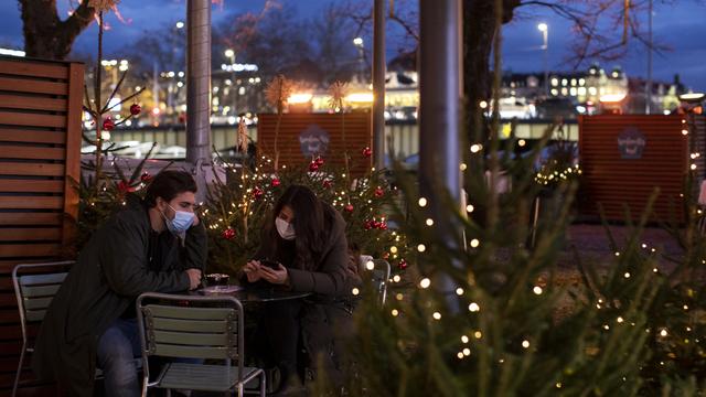 Deux personnes attablées, sur "l'île de Noël" sur la Limmat, le 19 novembre 2020 à Zurich. [Keystone - Alexandra Wey)]