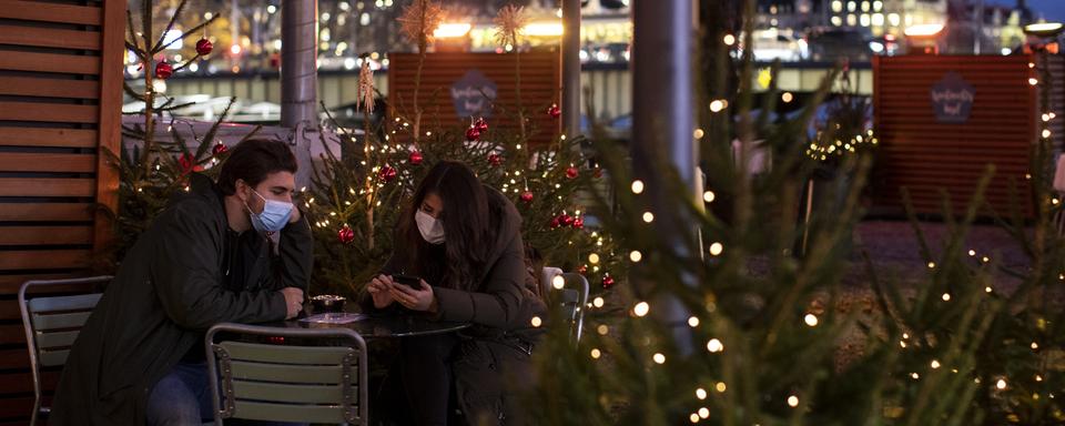 Deux personnes attablées, sur "l'île de Noël" sur la Limmat, le 19 novembre 2020 à Zurich. [Keystone - Alexandra Wey)]