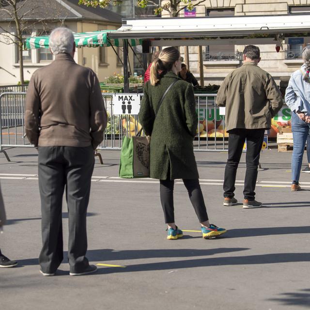 Des clients attendent au marché de Plainpalais à Genève en respectant la distance de sécurité. [Keystone - Martial Trezzini]