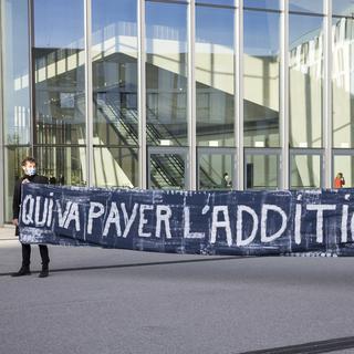 Des manifestant tiennent une banderole avec l'inscription "Qui va payer l'addition?", le 17 novembre 2020 sur le site de l'EPFL. [Keystone - Cyril Zingaro]