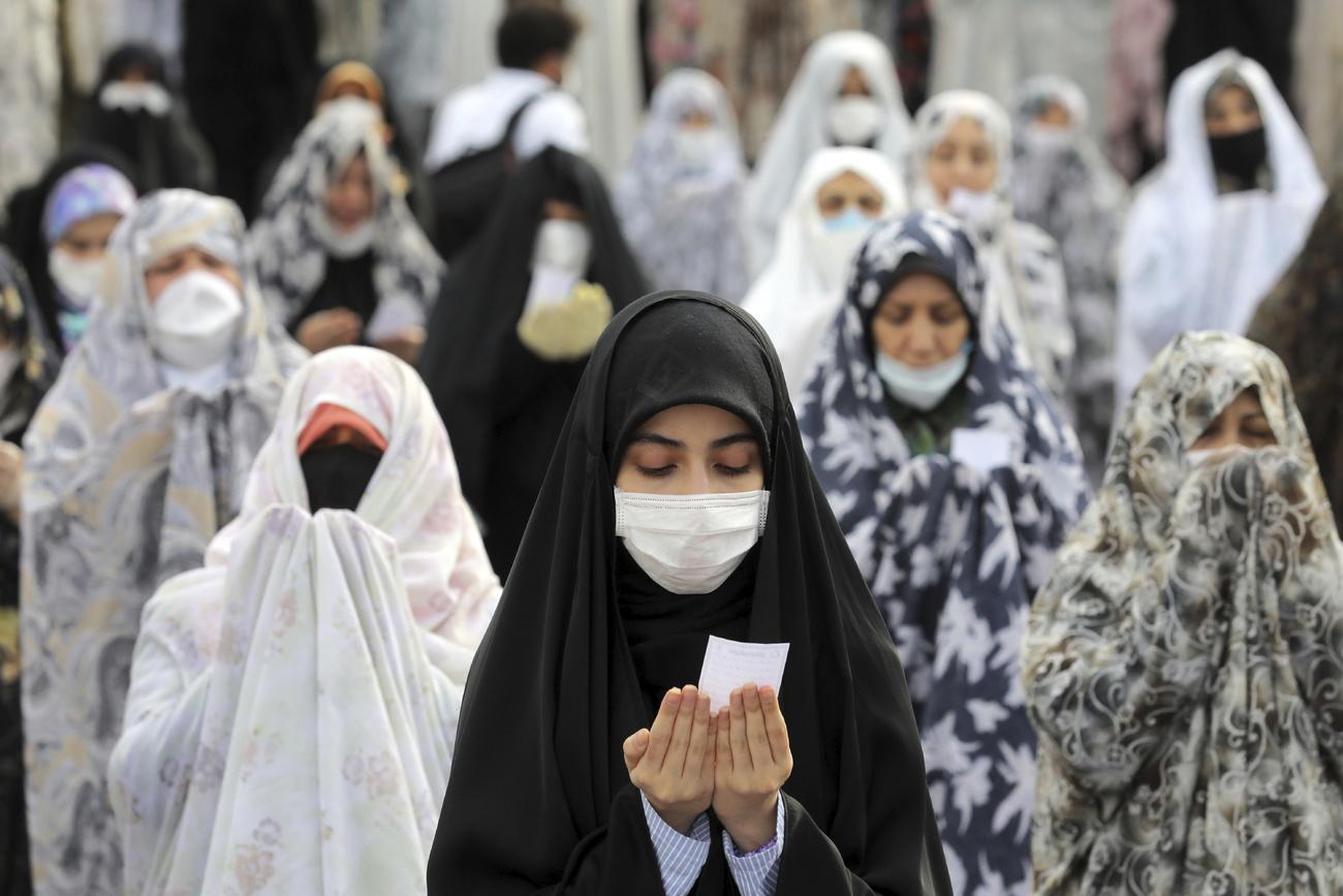 En Iran, des musulmanes prient masquées dans la cour d'un mausolée de Téhéran à l'occasion de l'Aïd. [Keystone - Ebrahim Noroozi]