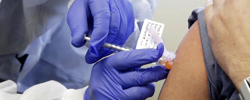 Un patient reçoit une injection dans le cadre de la première phase de l'étude de sécurité d'un vaccin potentiel pour COVID-19 à Seattle le 16 mars 2020. [Keystone - AP Photo/Ted S. Warren, File]