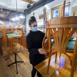 Une femme range les chaises d'un restaurant à Nyon, le 4 novembre 2020. [Keystone - Martial Trezzini]