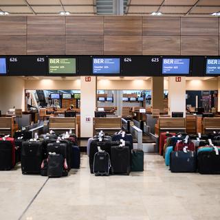 Des bagages déposés devant un comptoir d'enregistrement à l'aéroport de Berlin. [Keystone - EPA/CLEMENS BILAN]