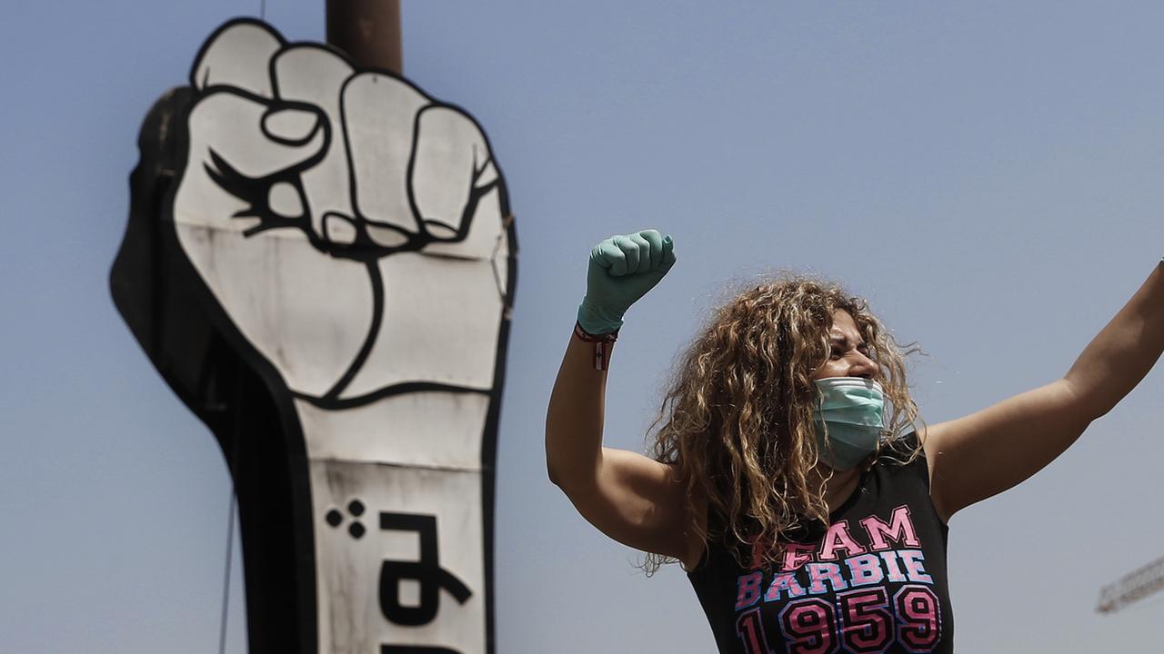 Une manifestante porte un masque et des gants durant une protestation dans un convoi de voitures au Liban le 22 avril 2020. [Keystone - Hussein Malla]