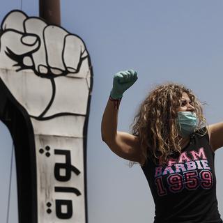 Une manifestante porte un masque et des gants durant une protestation dans un convoi de voitures au Liban le 22 avril 2020. [Keystone - Hussein Malla]
