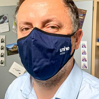 Nando Luginbühl portant un masque réutilisable offert par l'Uni de Neuchâtel. [Université de Neuchâtel]