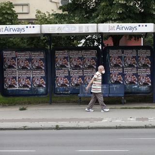 Un homme passe devant des affiches électorales en Serbie. [AP Photo/Keystone - Darko Vojinovic]