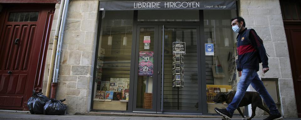 Un homme promène son chien à Bayonne le 30 octobre 2020, alors que la France est soumise à un nouveau confinement. [Keystone - AP Photo/Bob Edme]